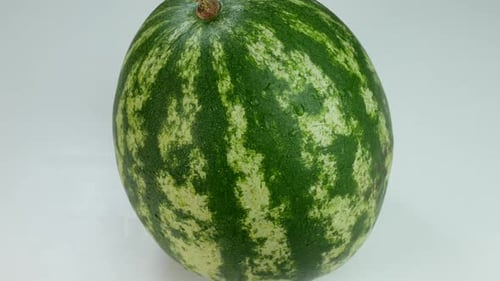 Wassermelone bedeckt mit Wassertropfen auf einer weißen Oberfläche
