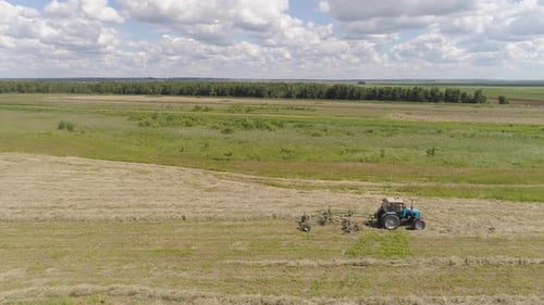 Trator com Rake Tedders no campo da fazenda