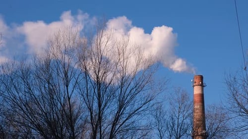 Smokestack Billowing White Smoke Against Bright Blue Sky