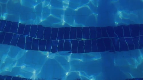 Fließendes Wasser im Schwimmbad leuchtet bei Sonnenuntergang, blaues transparentes Wasser des Schwimmbades