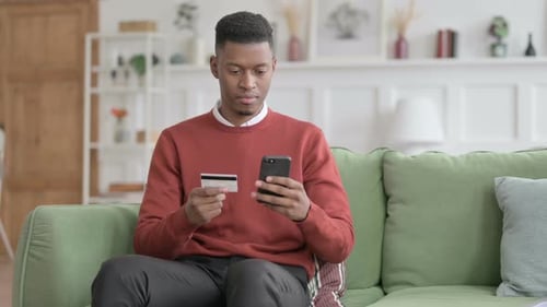 Man Using Smartphone and Credit Card at Home