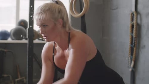 Muskulöse Frau benutzt Battle Ropes beim Training im Fitnessstudio