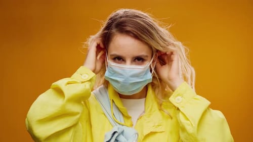 Young Woman Putting On Blue Surgical Face Mask