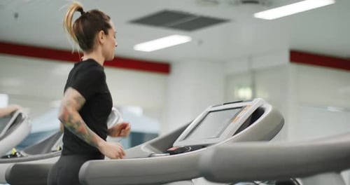 Young Woman Running on a Treadmill at Gym