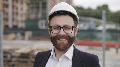 Porträt eines Bauarbeiters auf der Baustelle, der in die Kamera lächelt