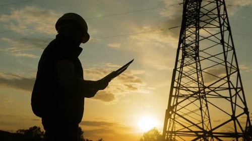 Silhouette eines Ingenieurs, der mit Strommasten auf einem Feld steht. Elektroingenieur mit hohem
