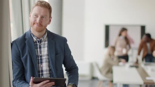 Smiling Man Uses Tablet in Bright Modern Office