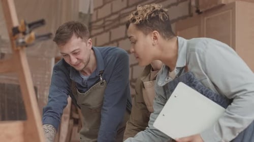 Carpenters Discussing Drawing Plan in Workshop