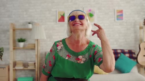 Cheerful Old Woman Pensioner Rocker with Gray Hair in Glasses Looking at the Camera Slow Mo