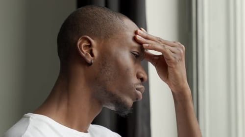 Man Indoors with Hand on Forehead, Pensive