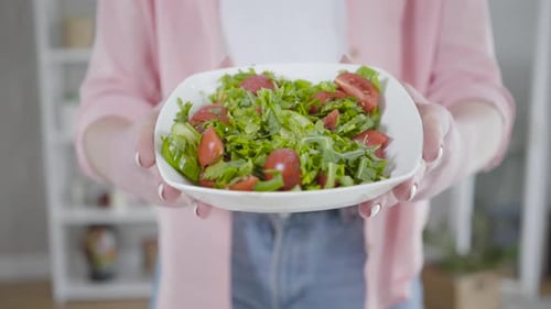 Woman Holds Fresh Salad Bowl in Home Kitchen