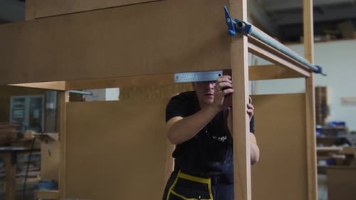Carpentry Works in Workshop Man Worker Standing in the Unfinished Wooden Construction and Measuring