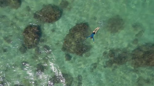 Aerial Slowmotion Shot of a Young Woman Snorkeling in a Clear Blue Sea Water