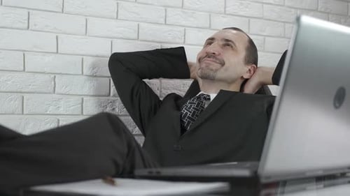 Relaxed Businessman Leans Back, Smiling in Office