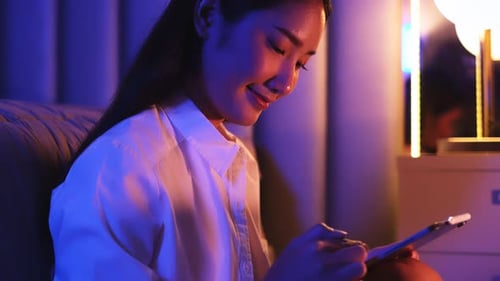 Young Asian beautiful woman enjoy using smartphone in bedroom at night time.