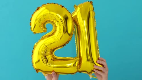 Hands Holding Golden Number Twenty-One Balloons