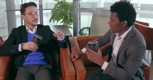 Businesspeople European and African Talking While Sitting in Chair in Office