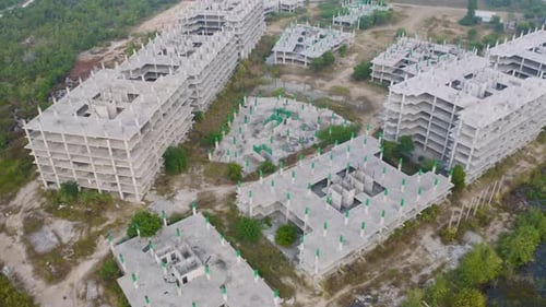 Aerial top view of abandoned apartment or hotel under construction site with structure.