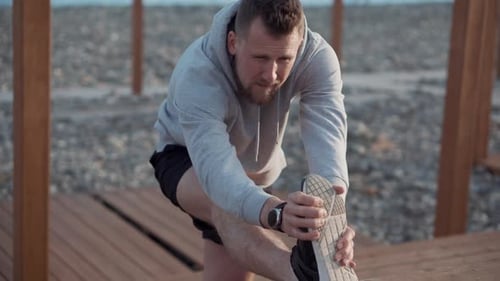 Bearded Man Stretching Leg at the Beach