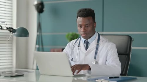 African Doctor Working on Laptop in Office