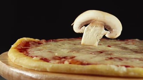 Mushroom Slice Falls On A Rotating Pizza On A Black Background