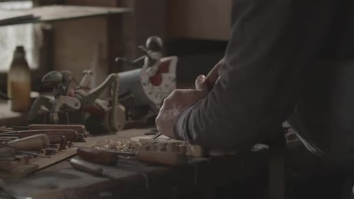 Adult Hand Carving Wood at Desk with Tools