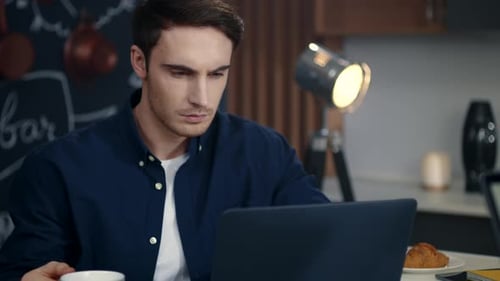 Joven empresario usando la computadora en la oficina en casa. Hombre concentrado trabajando en una computadora portátil