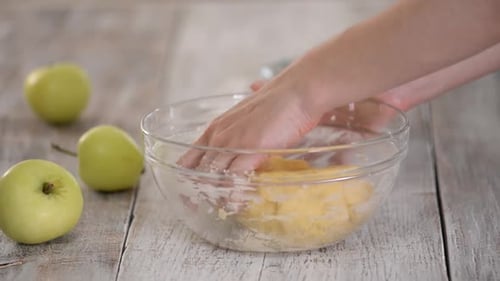 Hands Kneading Dough in Glass Bowl on Table