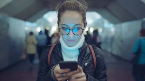 Woman Standing in the Entrance of a Subway Station Using a Smartphone