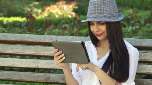 Woman Using Tablet on Park Bench, Smiling