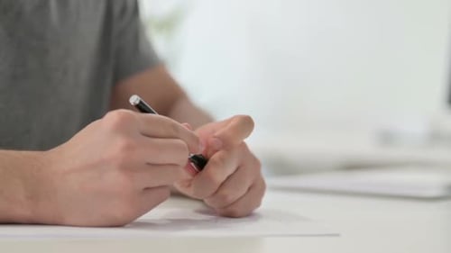 Hands of Anxious Man Tying to Write on Paper Close Up