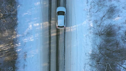 Close Up of White Car Riding Through Snowy Forest Road