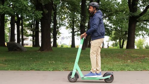 Mann im Helm fährt Elektroroller auf der Straße