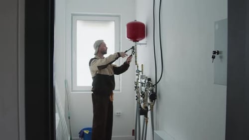 Plumber Working on Utility Pipes in a Utility Room