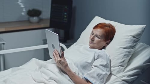 Woman Using Tablet Computer in Hospital Bed