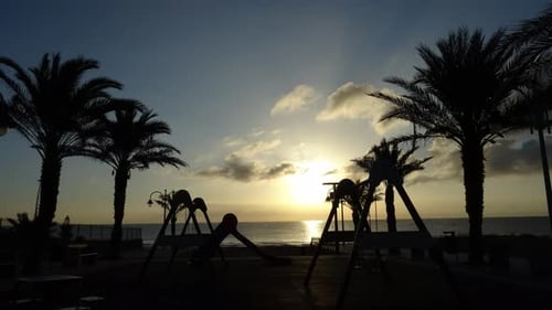 Aire de jeux pour enfants devant la plage au lever du soleil. TIMELAPSE.