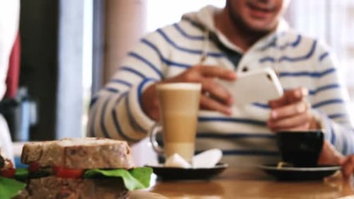 Friends Eat Sandwiches and Look at Smartphone