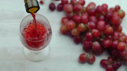 Wine Being Poured in Glass with Grapes