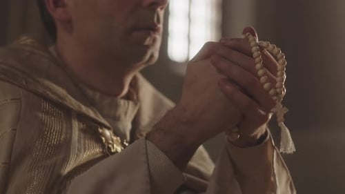 Priest with Rosary Beads Praying in Church