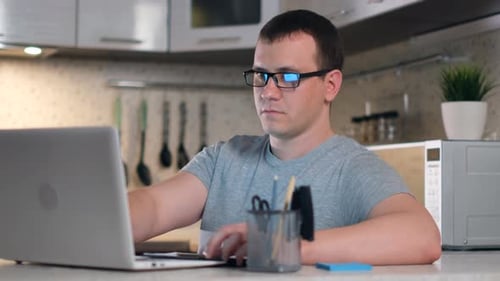 Man Working on Laptop and Writing in Notebook