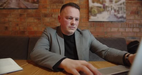 Man Working on Laptop, Reads Book