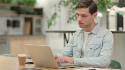Kreativer junger Mann schließt Laptop weg vom Büro