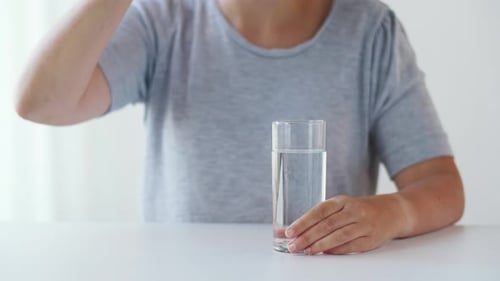 Adult Taking a Pill with Glass of Water