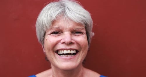 Senior Woman Laughing Close-Up in Front of Red Wall