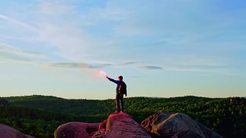 Adventurous Hiker Celebrates Sunrise with Red Smoke Flare
