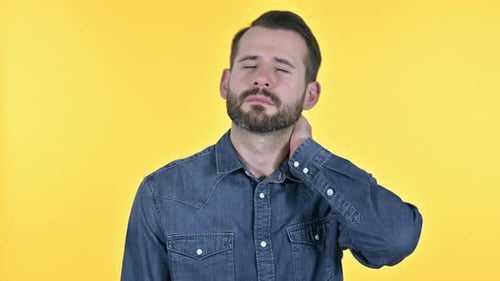 Man Rubs Neck in Pain Against Yellow Background