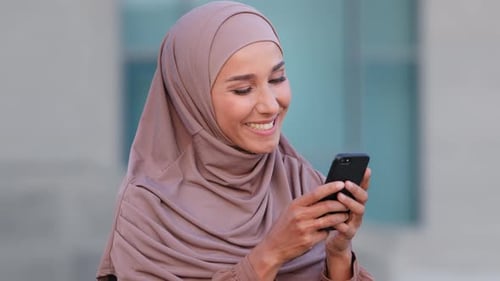 Woman Smiling Using Smartphone in Urban Setting