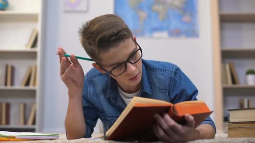 Teen Boy Studying on Floor with Books