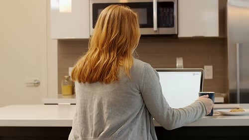 Woman Works At Laptop in Kitchen
