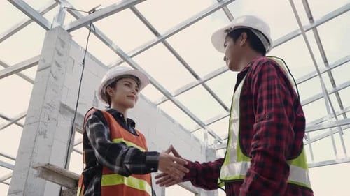 Asian architect engineer worker woman man in protective helmet and uniform shaking hands